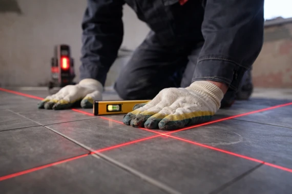 Pose de carrelage au sol avec contrôle des niveaux au laser pour une finition précise